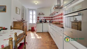 Cocina compacta con comedor, que presenta un salpicadero con estampado de espiga, horno integrado y refrigerador compacto.