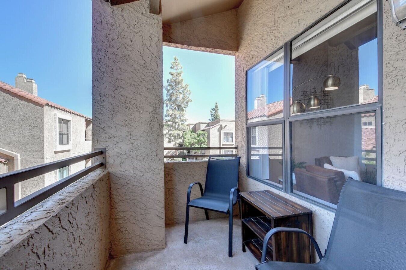 Un balcon avec une chaise, une petite table et une vue sur les immeubles voisins.