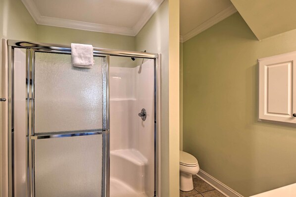Un baño con ducha de vidrio, inodoro y gabinete blancos.