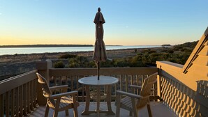 A wooden deck with a round table and two chairs, overlooking a beach and water. - Beachfront w/ Breathtaking Views! 1BR/2BA  Amenity Access included! (Seabrook Island)