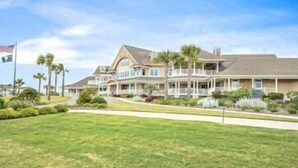 A large, multi-story house with a well-maintained lawn and palm trees. - Beachfront w/ Breathtaking Views! 1BR/2BA  Amenity Access included! (Seabrook Island)