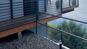 A waterfront property with a balcony overlooking a lake, a wooden deck, and a house number 7809. - CDA Lakeview Escape (Harrison)