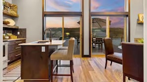 A modern kitchen with a large island, a dining area with a view, and a cozy seating space. - CDA Lakeview Escape (Harrison)