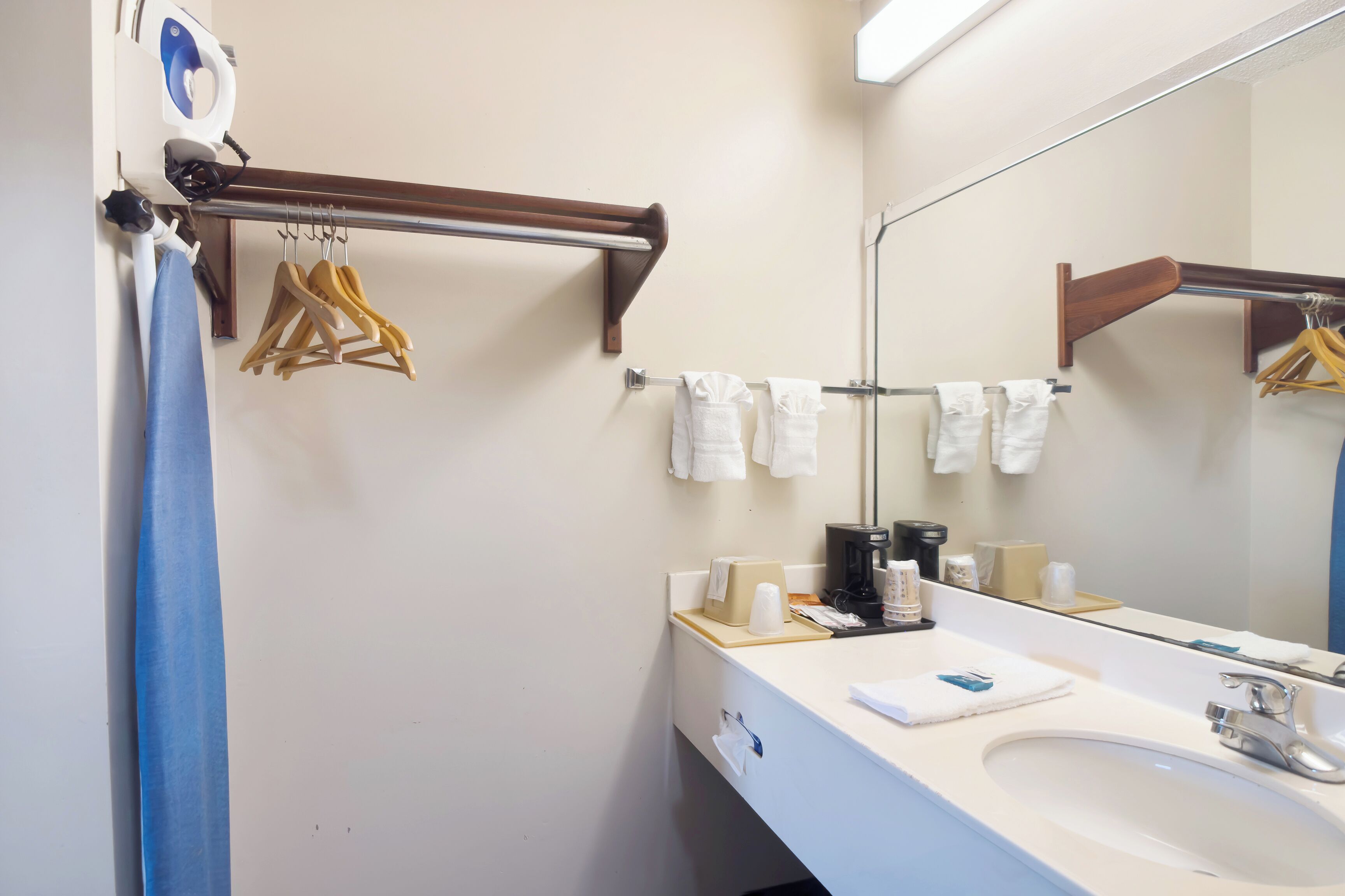A bathroom with a white sink, a mirror, a towel rack, and a towel dispenser.