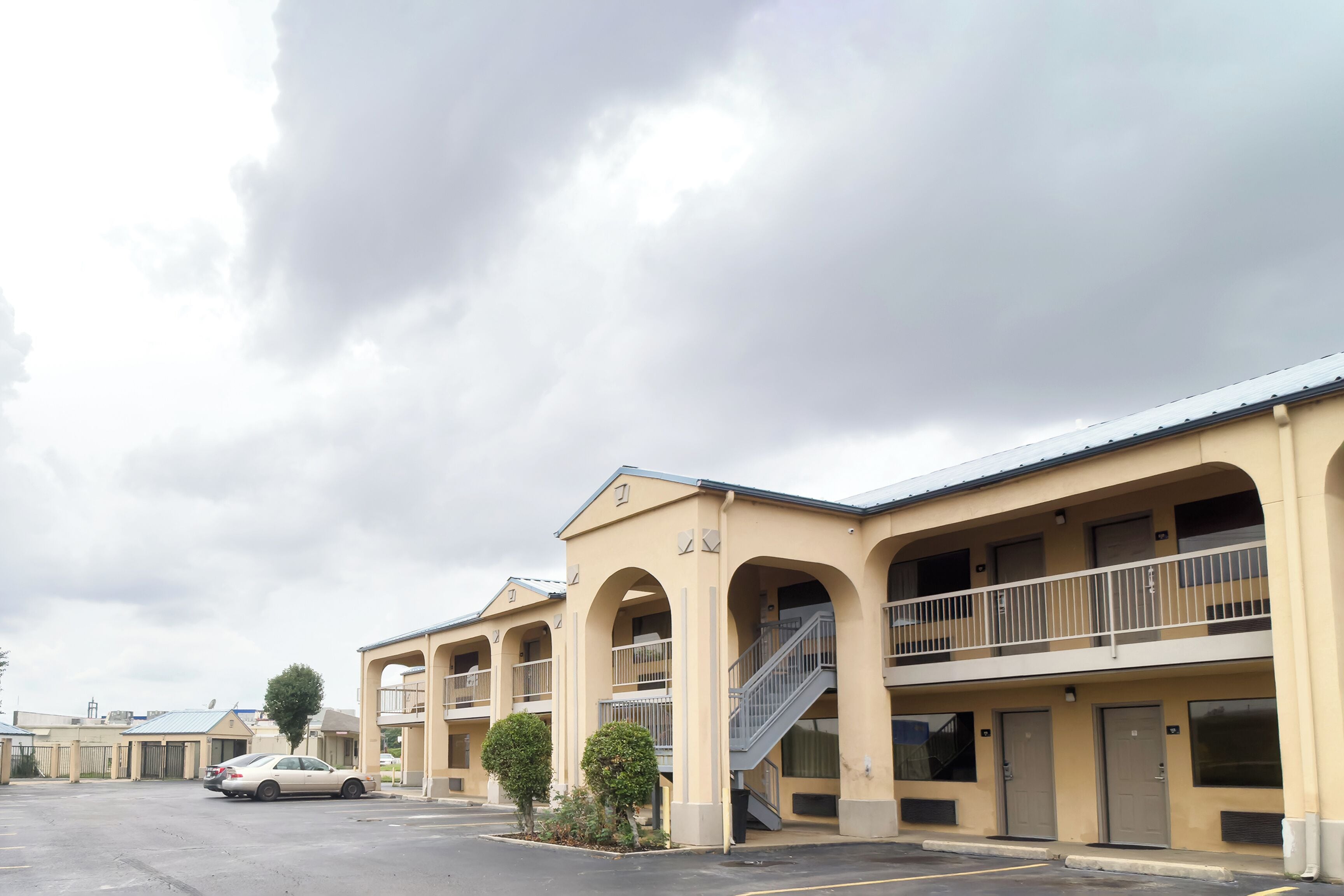 Un motel con varios balcones, estacionamiento y cielo despejado.