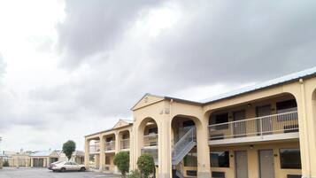 Un motel con varios balcones, estacionamiento y cielo despejado.