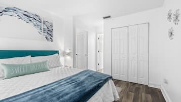 A bedroom with a bed, a teal headboard, a blue blanket, and a pillow with the text "SWEET DREAMS".