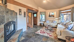 A living room with a stone fireplace, a sofa set, and a patterned rug. - Deck + Grill: Mtn Haven in Stanislaus Nat'l Forest (Arnold)