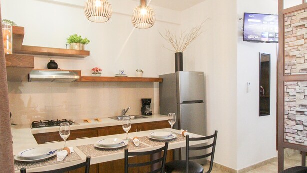 A modern kitchen with a dining area, featuring a central island, pendant lighting, and a built-in refrigerator. - Loreto host (Loreto)