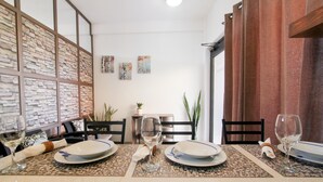 A dining area with a table set for four, a brick wall with a window, and a plant on the side. - Loreto host (Loreto)