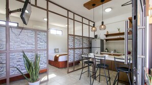 A modern hotel room with a stone wall partition, a bed, a dining area with a table and chairs, and a kitchen area with a refrigerator and a sink. - Loreto host (Loreto)