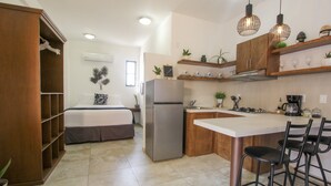 A compact kitchen with a refrigerator, wooden cabinets, and a bar area with stools. - Loreto host (Loreto)
