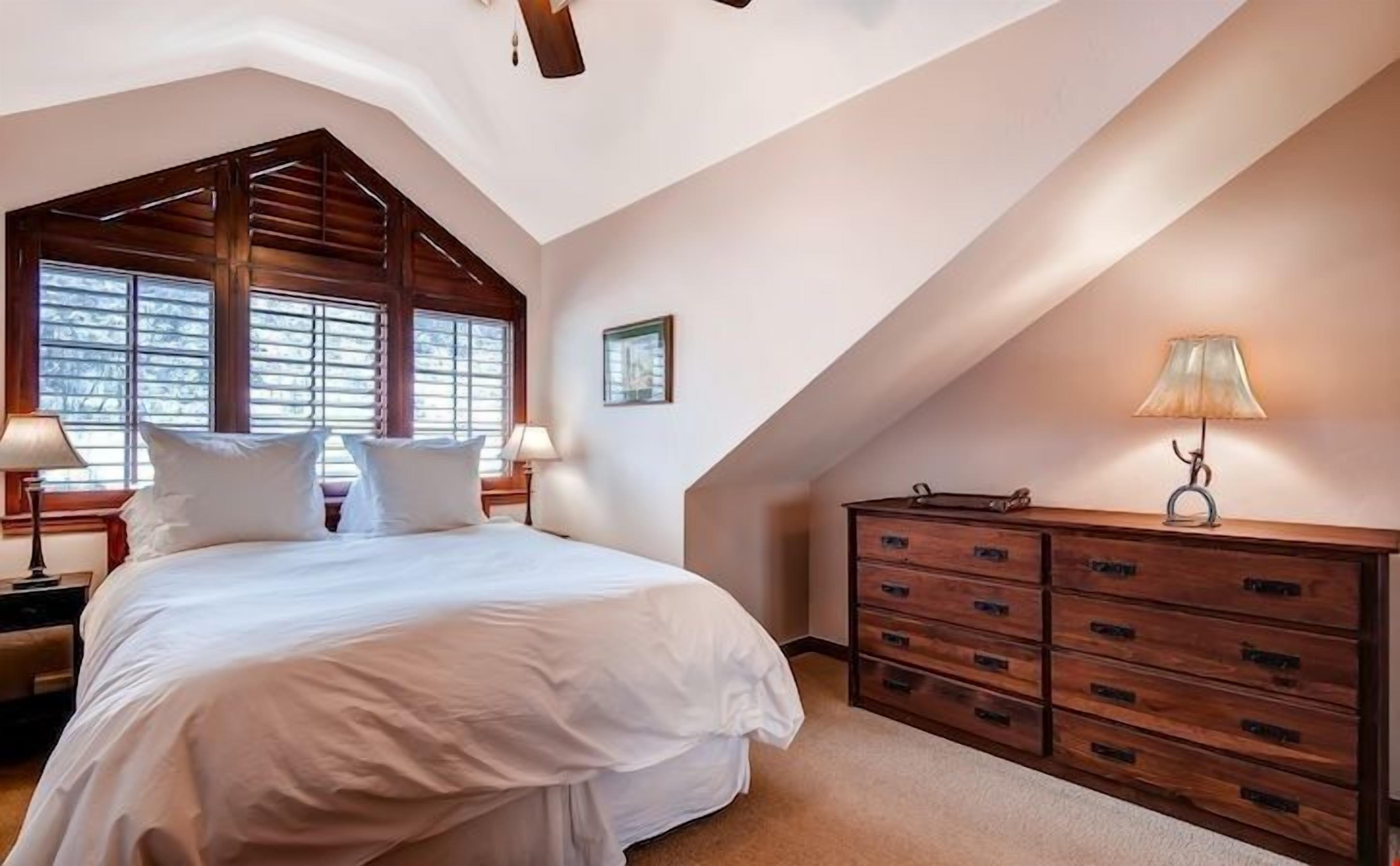 Un dormitorio con una cama grande, cómoda de madera y techo inclinado.