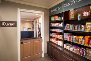A pantry area with shelves stocked with various snacks and a sign indicating the location.
