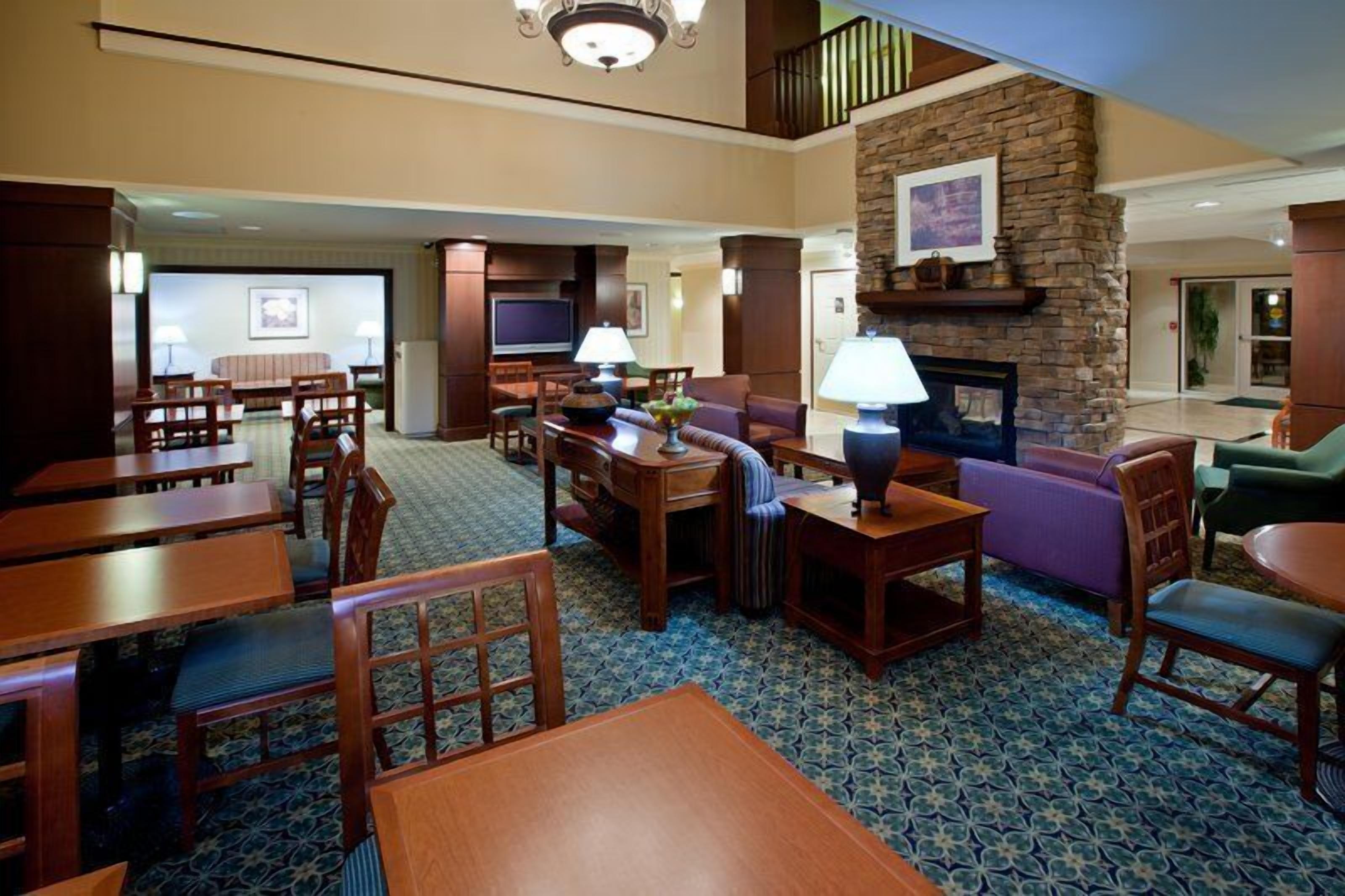 A hotel lobby with a fireplace, seating area, and a television.