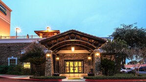 A hotel entrance with a stone facade, a covered entryway, and a parking lot. - Studio | Free Breakfast + Outdoor Pool and Hot Tub (San Antonio)