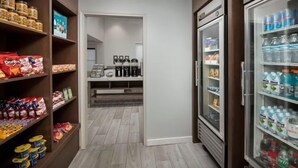 A pantry with shelves stocked with snacks and beverages, a refrigerator, and a coffee machine. - Studio | Free Breakfast + Outdoor Pool and Hot Tub (San Antonio)