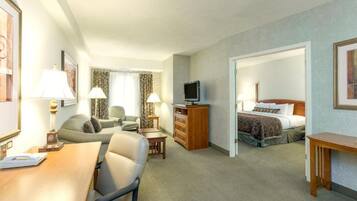 A hotel room with a dining area, a TV, a bed, and a desk.