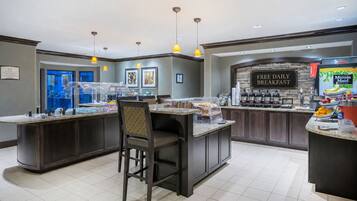 A breakfast bar with a sign for 'FREE DAILY BREAKFAST' and a 'Minute Maid' juice dispenser.