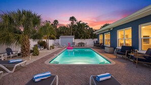 Un jardin avec une piscine, des chaises longues et un espace repas.