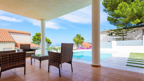 Un espacio al aire libre techado con muebles de mimbre y una piscina.
