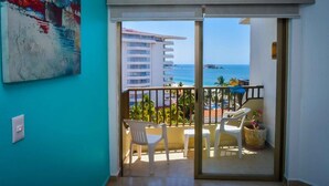 A balcony with a view of the ocean, white plastic chairs, a table, and a potted plant. - Condominio 02 recamaras Enna Inn Ixtapa (Ixtapa)