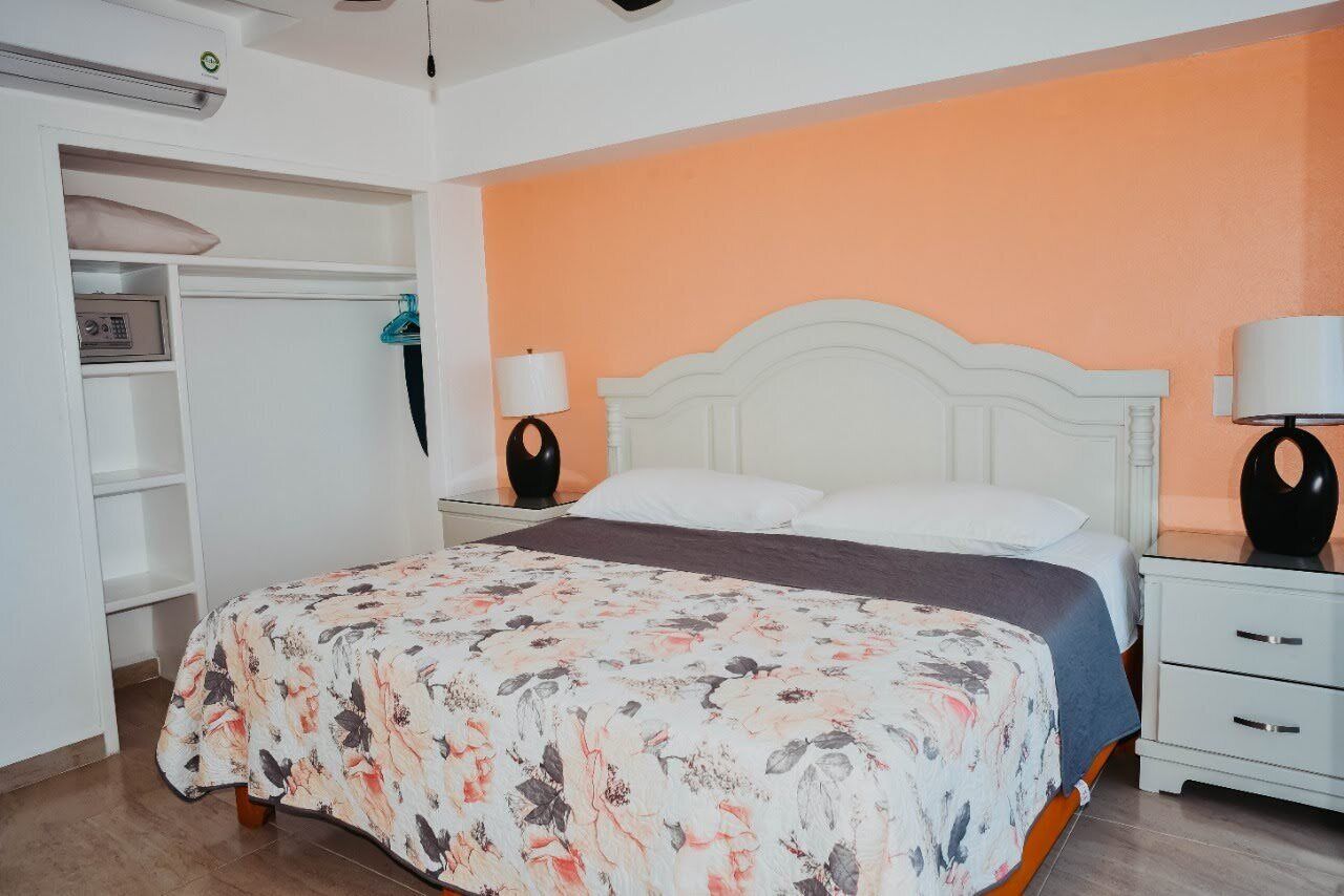 Une chambre à coucher comprenant un lit, des tables de chevet, une armoire et un radiateur mural.