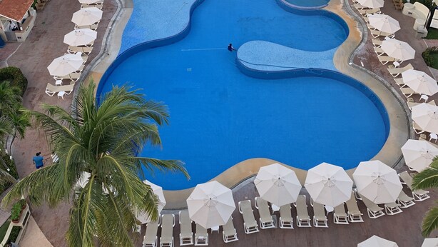 A large, multi-tiered swimming pool with sun loungers and umbrellas, surrounded by palm trees, with a beach and ocean view. - Condominio 02 recamaras Enna Inn Ixtapa (Ixtapa)