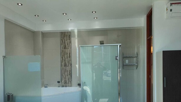 A modern hotel room with a large bed, a glass-enclosed shower, and a separate bathroom. - Hotel Golden Sky (Pariñas)