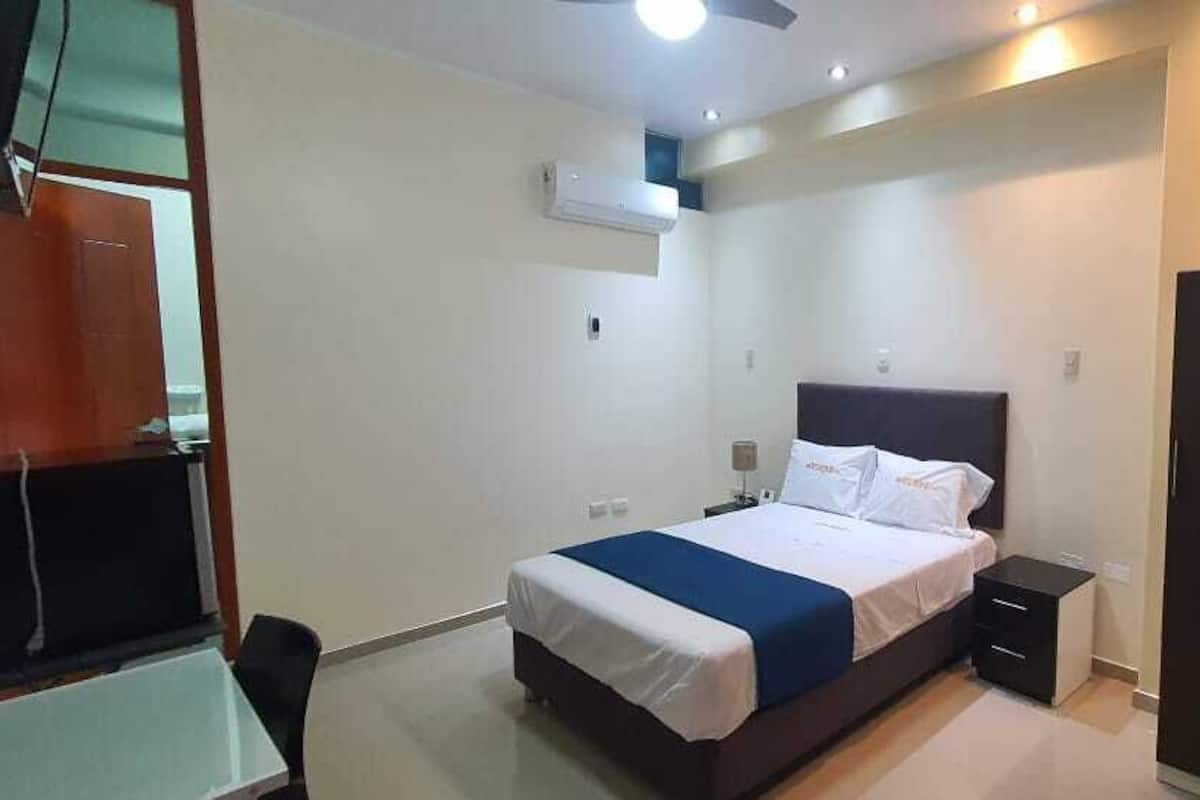 A bedroom with a bed, bedside tables, a wardrobe, and a ceiling fan.