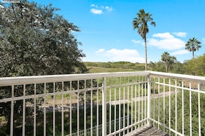 A white metal railing overlooking a grassy area with trees and a clear sky.