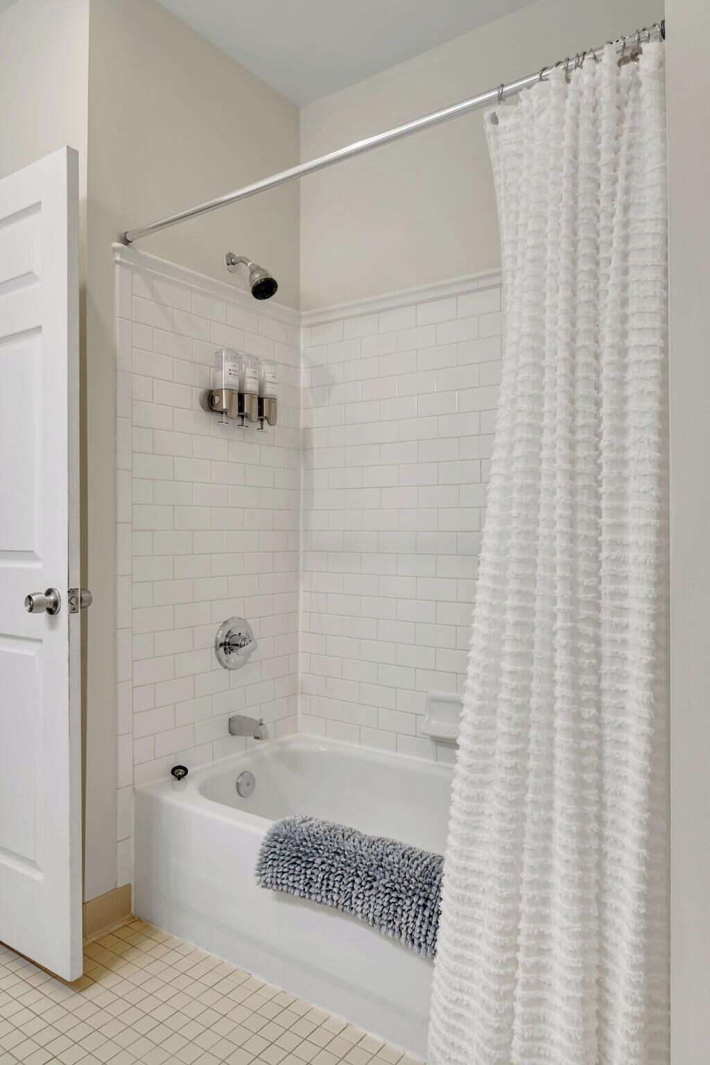 A bathroom with a white bathtub, a shower curtain, and a towel rack.