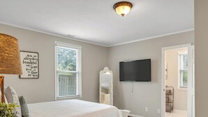 Quarto com uma cama grande, televisão de tela plana na parede e janela com persianas.