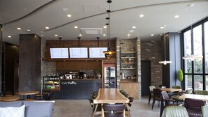 Un café moderno con una mesa de comedor de madera, sillas de cuero y una pizarra con el menú.