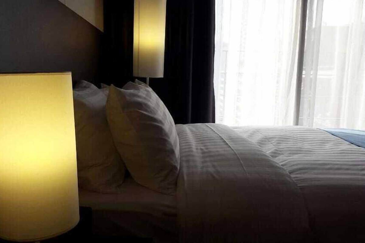 Une chambre d’hôtel avec un lit, des oreillers et une grande lampe.