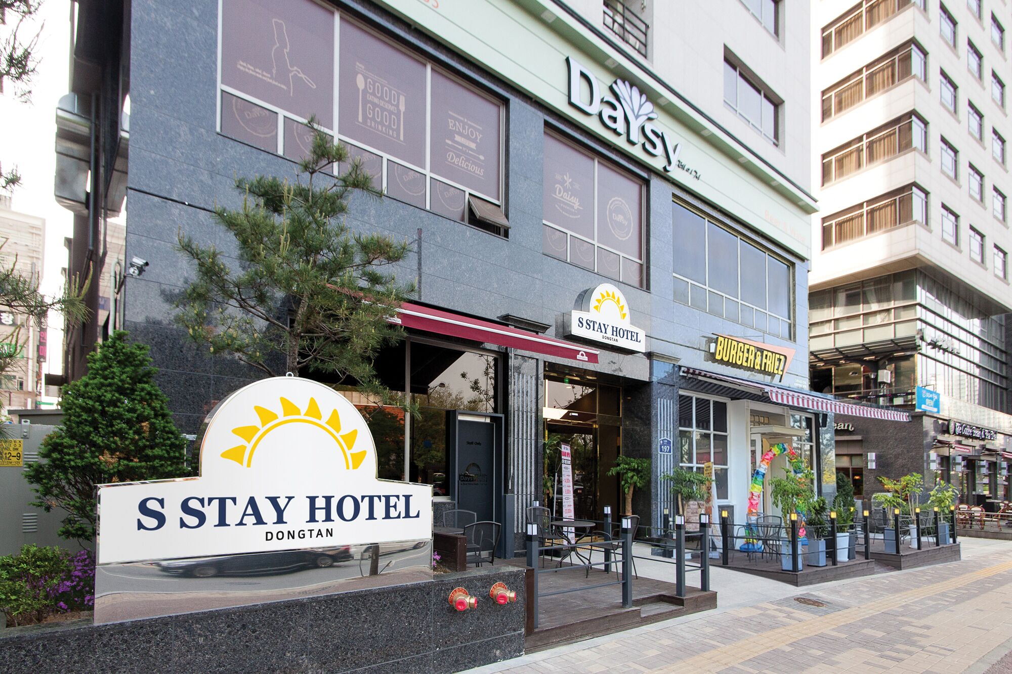 The exterior of S Stay Hotel with a sign for Burger & Fries.