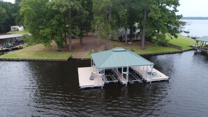 Un barco amarrado con una zona de estar techada y un edificio cercano.