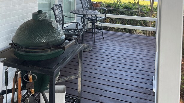 Un espacio al aire libre techado con una parrilla, sillas y vistas al agua.
