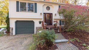 A single-story house with a front garage, a front porch with a bench, and a small garden area. - Gilford Central Retreat - For all your Vacation Needs! (Gilford)