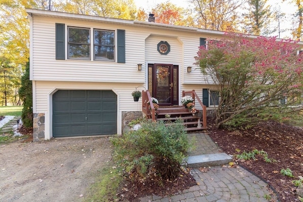 Une maison de plain-pied avec un garage à l’avant, un porche avec un banc et un petit jardin.