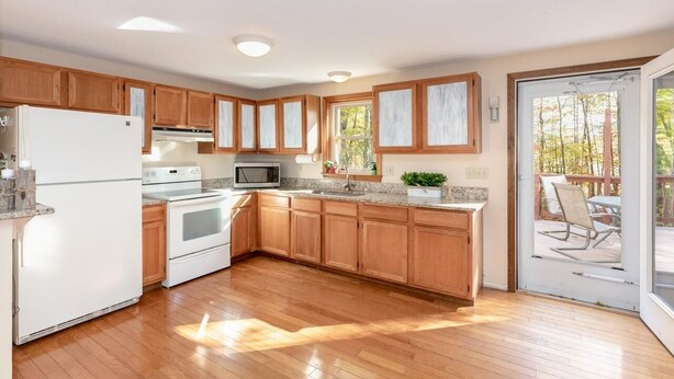 A modern kitchen with wooden cabinets, a white refrigerator, a stove, and a microwave. - Gilford Central Retreat - For all your Vacation Needs! (Gilford)