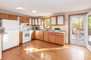 Une cuisine moderne avec des meubles en bois, un réfrigérateur blanc, une cuisinière et un four à micro-ondes.