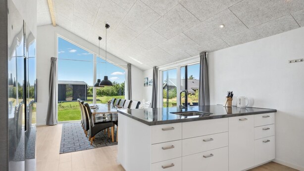 A modern kitchen with a large island, white cabinetry, and a view of a garden. - Stunning home in Tarm with kitchen (Tarm)