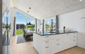 A modern kitchen with a large island, white cabinetry, and a view of a garden. - Stunning home in Tarm with kitchen (Tarm)