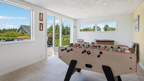 A room with a foosball table, large windows, and a view of a house and garden. - Stunning home in Tarm with kitchen (Tarm)