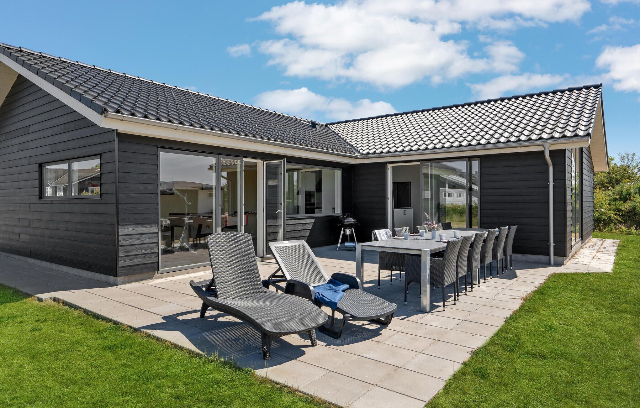 A modern house with a patio area featuring outdoor furniture and a dining table.