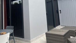 A modern house with a covered patio, outdoor seating, and a large window. - Beach side duplex (punaauia)