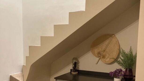 A staircase with a light wood finish, a dark countertop, and a potted plant with purple flowers. - Beach side duplex (punaauia)
