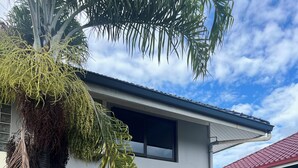 A modern house with a white exterior, a red roof, and a garage. - Beach side duplex (punaauia)