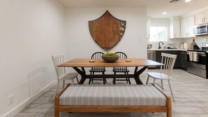 Un comedor con una mesa y sillas de madera, un banco y un escudo decorativo en la pared.
